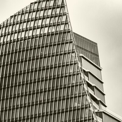 Close-up architectural detail of a modern skyscraper corner where polished steel meets glass